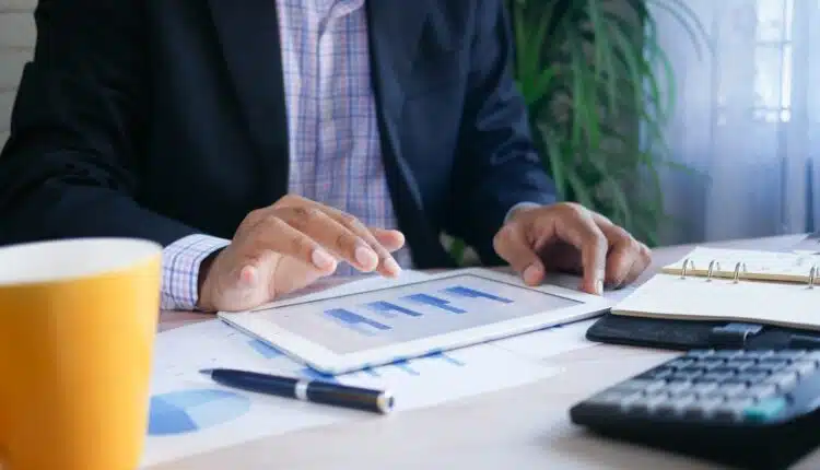 person in black suit jacket holding white tablet computer